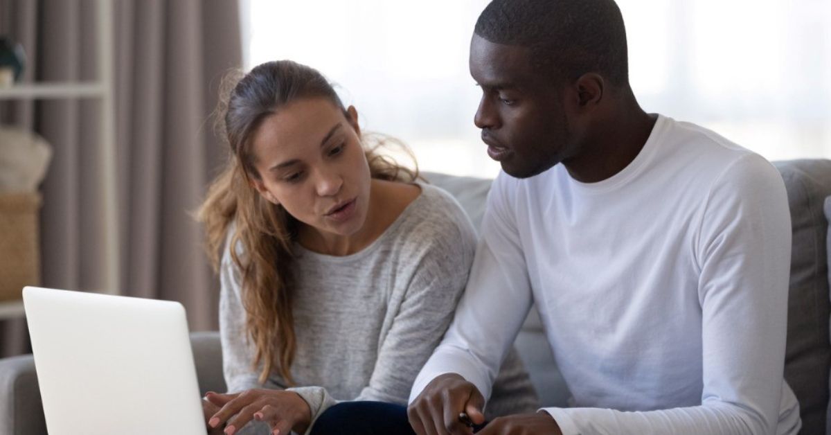 A young millennial couple look worried while reviewing financial documents.