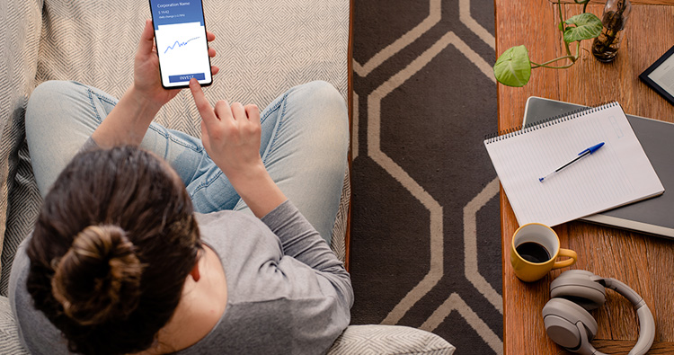 an image from above of a woman sitting on a couch with a mobile phone in her hand