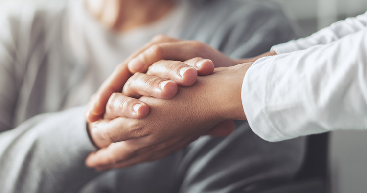 A close-up image of two women grasping each other hands.