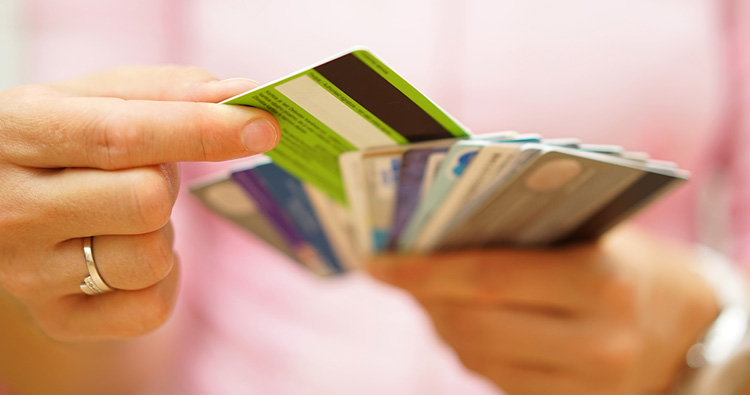 A close-up image hands holding many credit cards