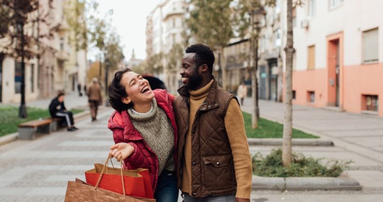A young couple laugh together while shopping for the holidays.
