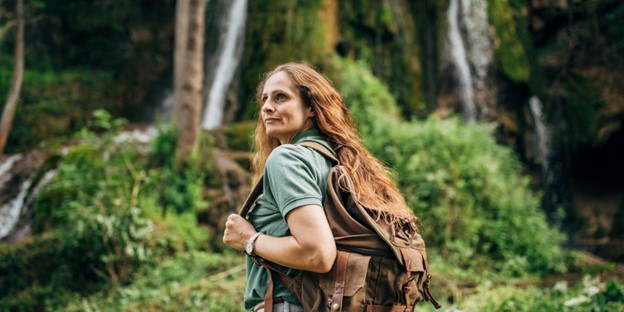 A woman walks alone in a forest.