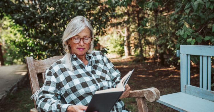 A woman sits in the park reading a book.