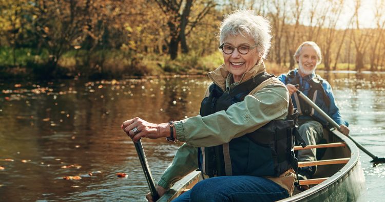 A retired couple canoe down a river together.