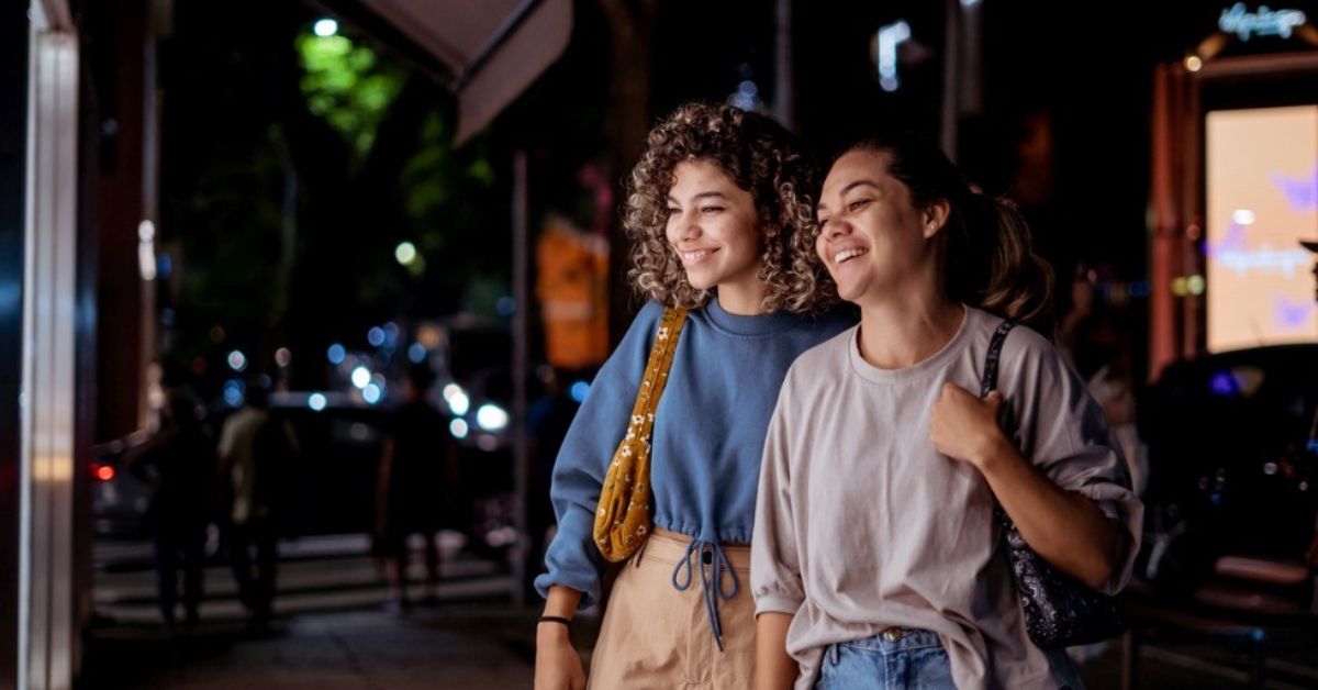 A mother and daughter smile while looking at a shop window.