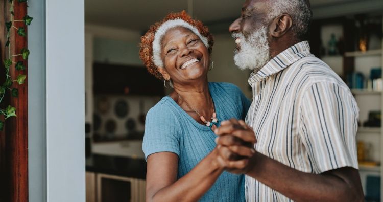 A retired couple dance together in a kitchen