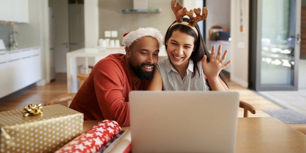 A young couple in holiday garb video chat with family to celebrate