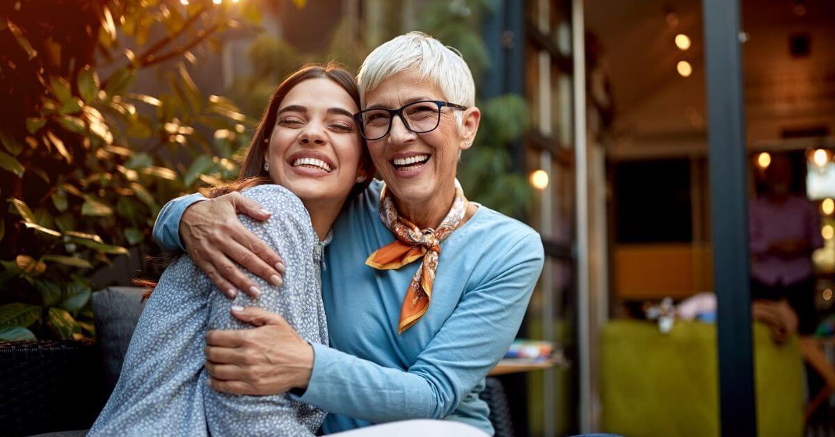 An older woman give a big hug to her adult granddaughter.