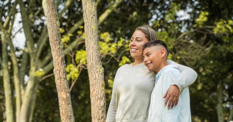 A mother wraps her arm around her young teenage son