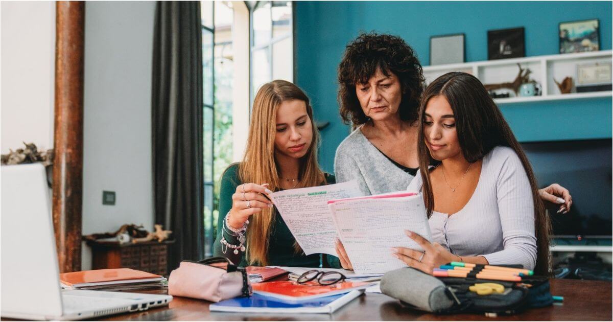 A mother helps her teen daughters prep for college