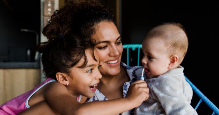 A mother holds her toddler and baby