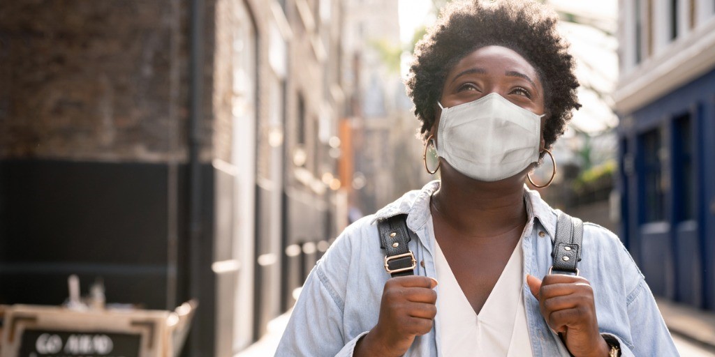 A women in a face mask looks up while outside walking