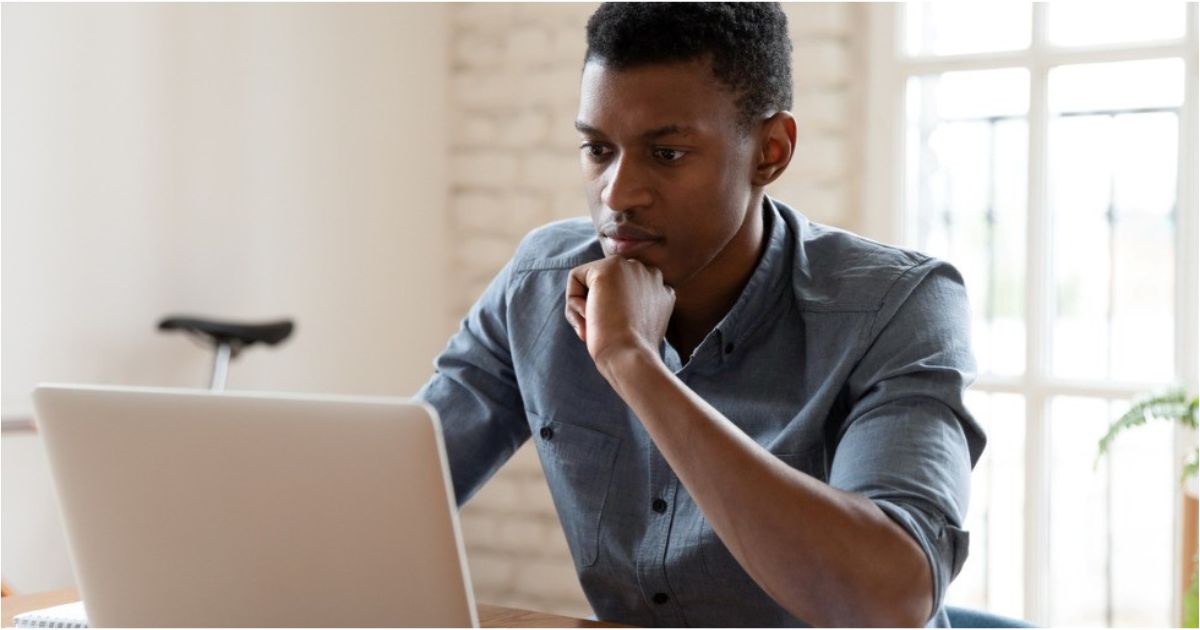 A young man looks at his computer screen with concern.