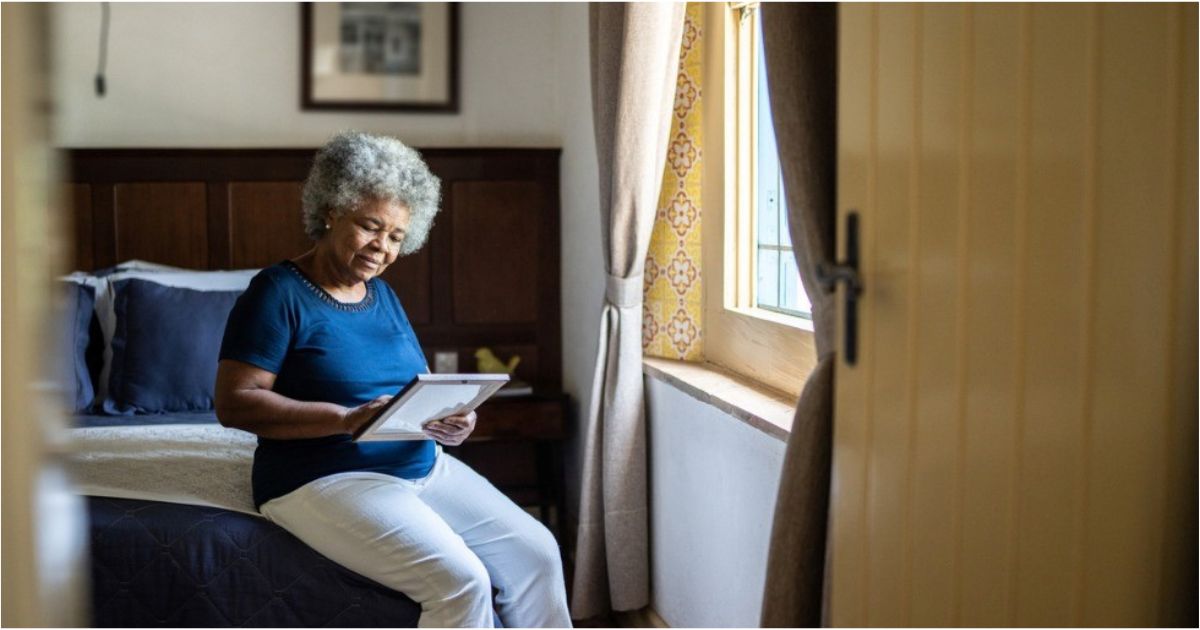 An older woman looks somberly at a photo of a loved one.