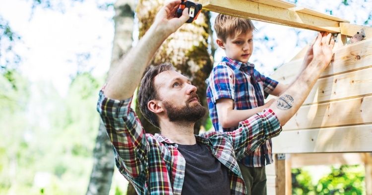 A father builds a treehouse with his young son.