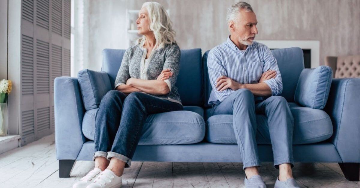 An older couple look away from each other, upset