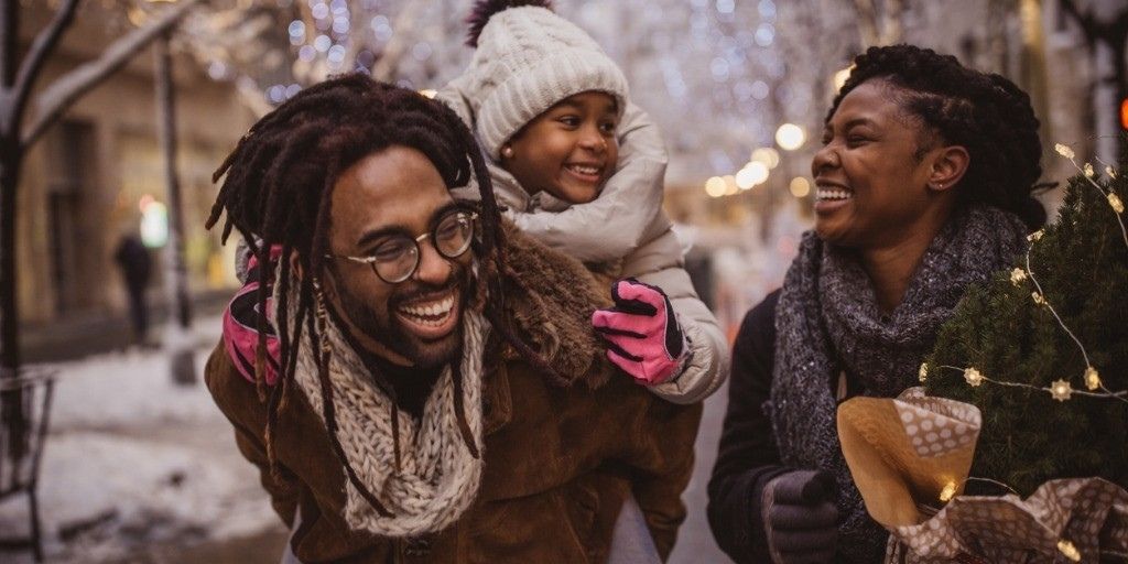 A young black family walk together while shopping for the holidays