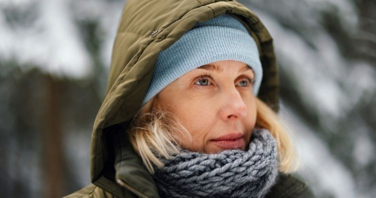 A woman in winter gear looks out at the woods