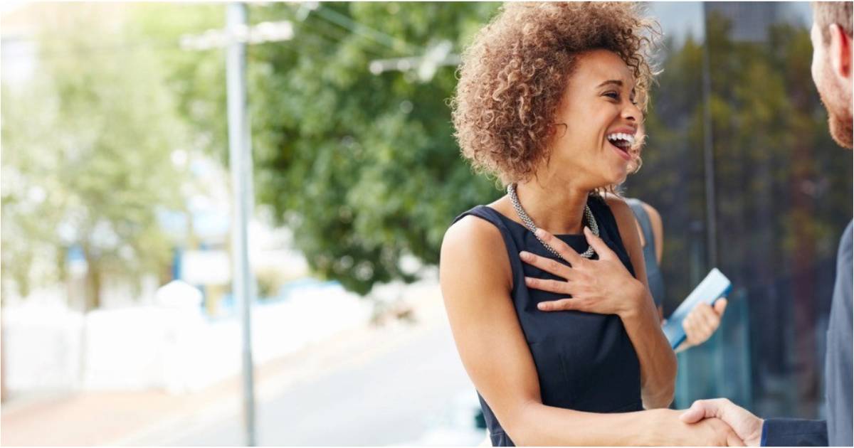 A woman grins boradly while accepting an offer for a new job.