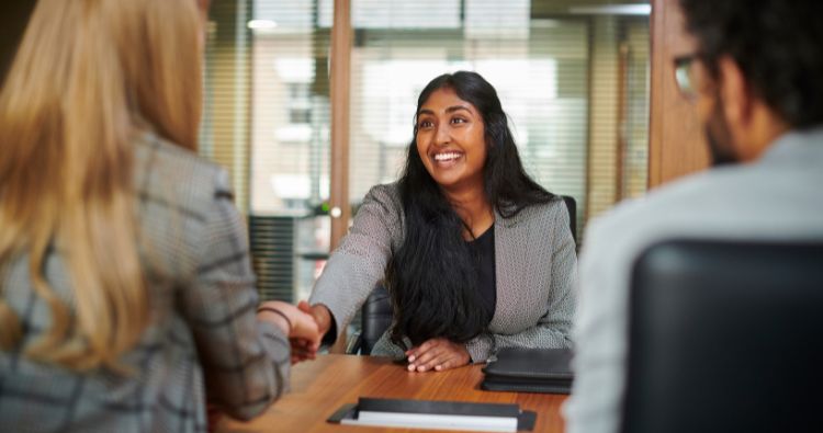 A woman grins boradly while accepting an offer for a new job.