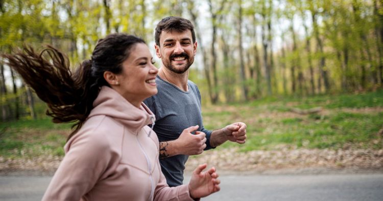 A young couple running outdoors together