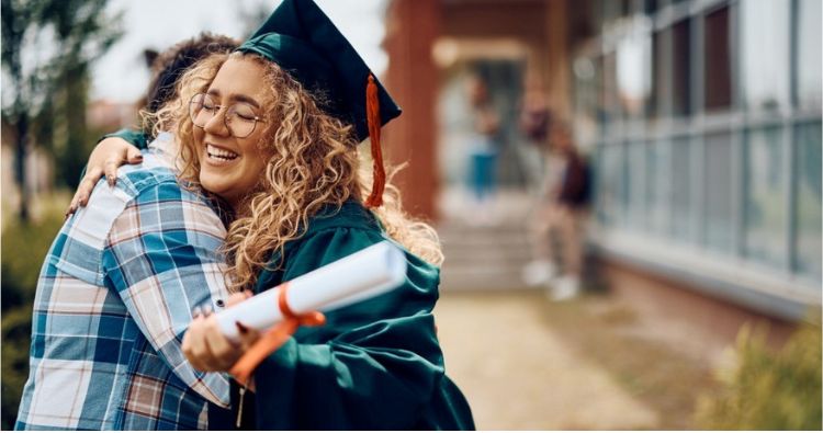 A young woman smiles brightly while holding her diploma.