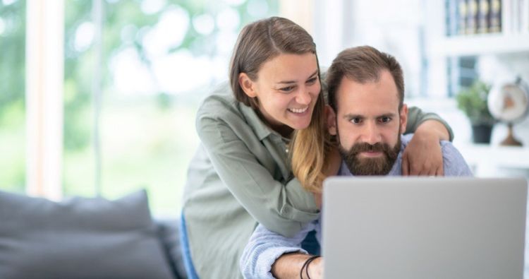 A couple smile while researching financial topics on the web.