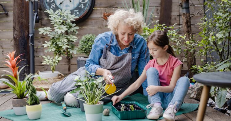 A grandmother showing her granddaughter how to plant a garden.