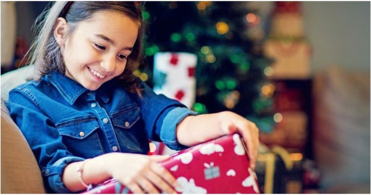 A girl looking at a wrapped Christmas present