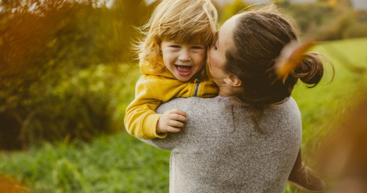 A mother carrying her smiling child in her arms