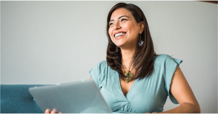 A young woman looks happy as she uses her tablet.