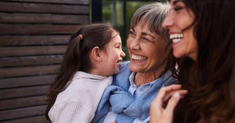 A grandmother embraces her daughter and granddaughter.