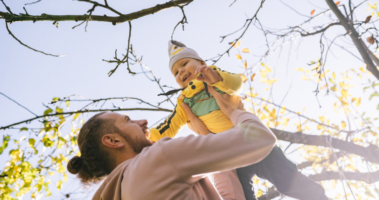 A father raises his son to the sky.