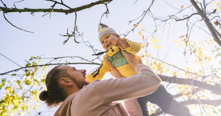 A father raises his son to the sky.