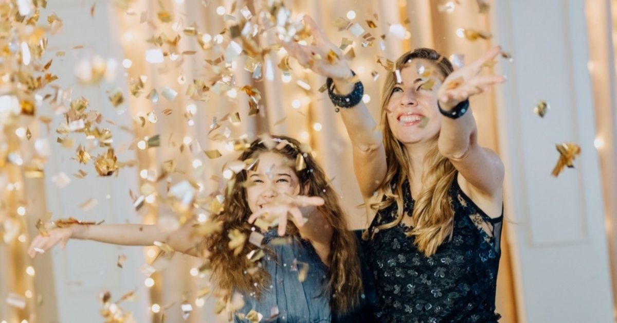 A mother and her young daughter toss confetti