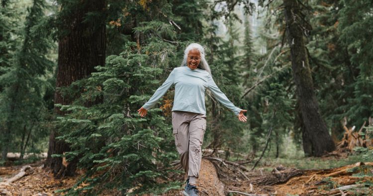 An older woman hiking in the woods.