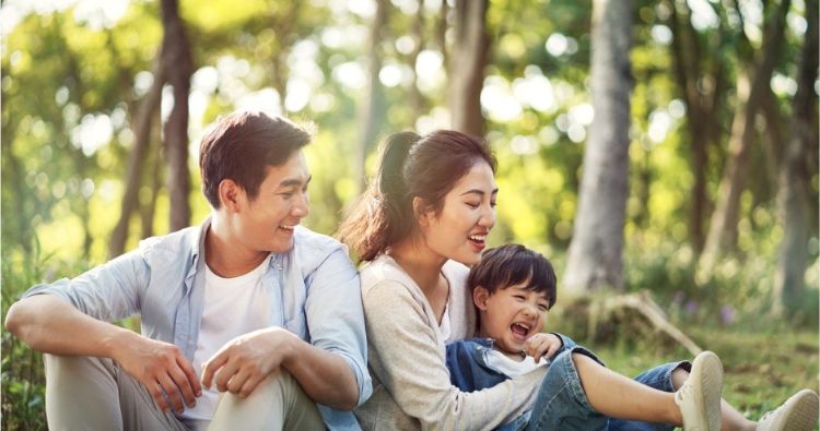 A young family enjoy a day in the sun while in the park.