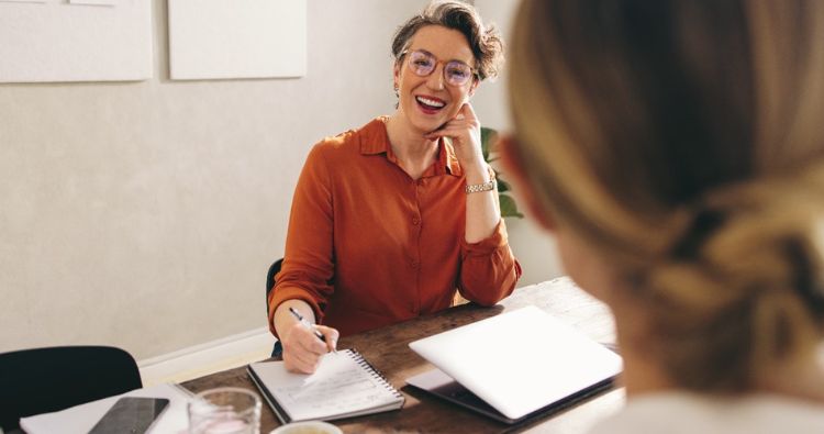 A woman smiles while being interviewed for a job.