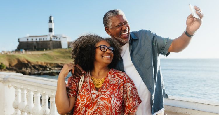 Two retirees take a selfie while sightseeing at the ocean.