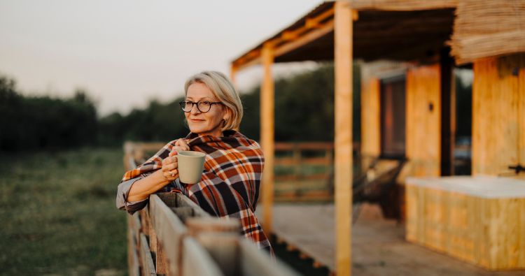 A woman enjoys a cup of coffee wrapped in a blanket.