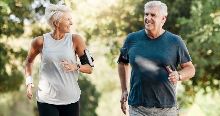A retired couple go on a run outside in the park.
