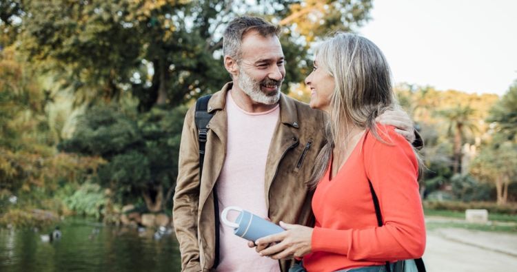 A retirement-aged couple walk together in a park.