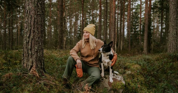 A woman hiking in the woods with her dog.