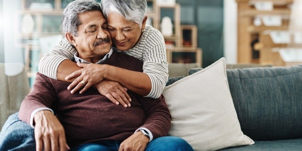 An older married couple embrace sweetly