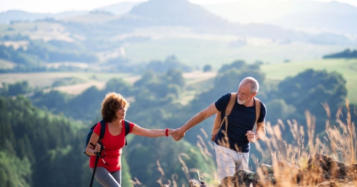 An older couple hike up a hill together.