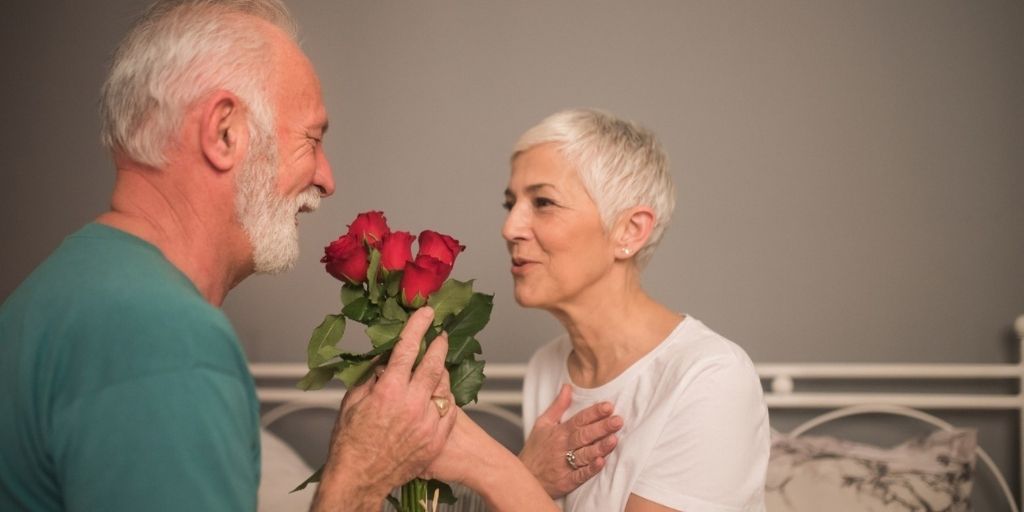 A middle-aged man give his wife a bouquet of roses