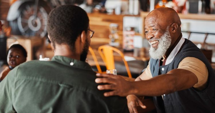 A father smiles at his son while putting a hand on his shoulder