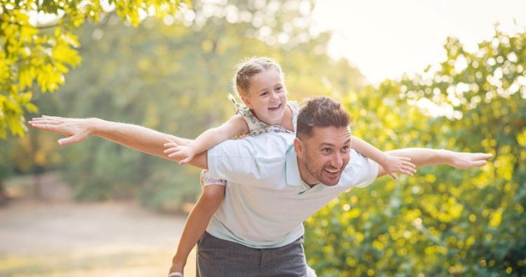 A young fathers gives his daughter a piggyback ride.