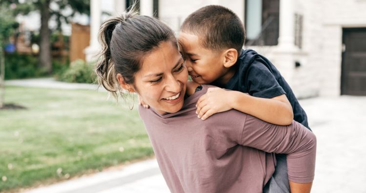 Young mother giving her young child a piggy-back ride