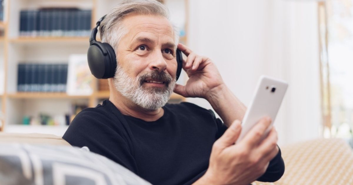 An older man listen to a podcast to help him with financial literacy.